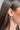 Side view of model wearing the Holly Silver Glitter Hoop which features mini open silver glitter hoops with holly flower designs.