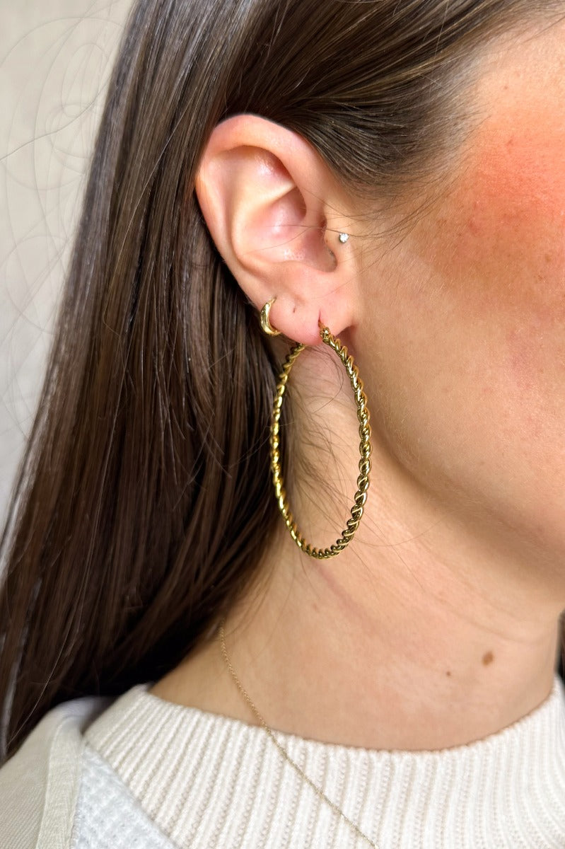 Side view of model wearing the Kristen Gold Rope Closed Hoop which features large gold roped open hoops.