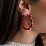 Close up view o fmodel wearing the Patricia Pearl Red Hoop which features medium red open hoops with mini pearl details.