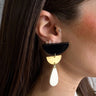 Side view of model wearing the Gemma Black Multi Shape Dangle Earring which features black half moon stud linked with a small gold half moon and a white teardrop.