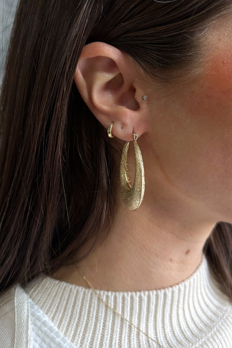 Front view of model wearing the Jessica Gold Glitter Scoop Closed Hoop which features open scooped hoops with gold glitter.