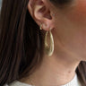 Front view of model wearing the Jessica Gold Glitter Scoop Closed Hoop which features open scooped hoops with gold glitter.