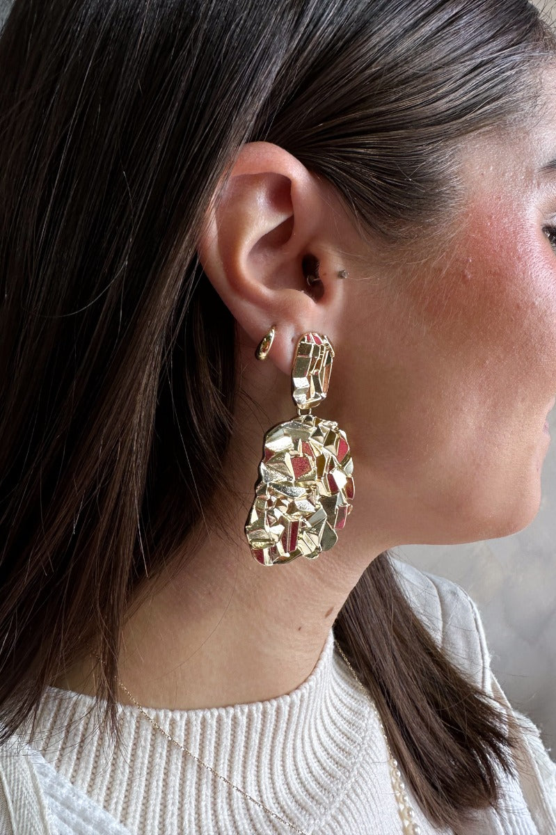 Side view of model wearing the Patricia Gold Textured Dangle Earring which features gold, woven teardrop shape dangles linked together.
