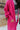Side view of model wearing the You Are Fabulous Cardigan which features hot pink knit fabric with a long-line hem, front pockets, and long balloon sleeves with ribbed cuffs.