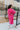 Back view full body of model wearing the You Are Fabulous Cardigan features hot pink knit fabric with a long-line hem, front pockets, and long balloon sleeves with ribbed cuffs.