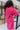 Back close up view of model wearing the You Are Fabulous Cardigan which features hot pink knit fabric with a long-line hem, front pockets, and long balloon sleeves with ribbed cuffs.