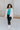 Full body view of model wearing the Get Cozy Jacket which features plush ivory fabric with a checkered pattern, a zip up front, long sleeves and a collared neckline.