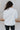 Back view of model wearing the Get Cozy Jacket which features plush ivory fabric with a checkered pattern, a zip up front, long sleeves and a collared neckline.
