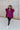 Full body view of model wearing the This Is My Jam Sweater which features loose-knit magenta fabric with cuffed 3/4-length sleeves, a high-low hemline with side slits, and a rounded neckline.