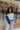 Front view of model wearing the Don't Block My View Sweater which features ivory, orange, royal blue and aqua blue knit fabric, a round neckline, balloon sleeves with ribbed trim, and a cropped waist. Front of the sweater is tucked. 