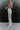 Side view of model wearing the You Should Be Dancing Pant which features taupe crinkle fabric, a zipper and hook closure, two front pockets and wide straight legs.