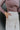 Close up view of model wearing the You Should Be Dancing Pant which features taupe crinkle fabric, a zipper and hook closure, two front pockets and wide straight legs.
