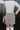 Back view of model wearing the Sitting Pretty Skirt which features a cream and brown geometric pattern fabric with frayed trim, a zipper on the side, and a lining.