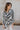 Front view of model wearing the Positive Vibes Top which features satin fabric with a cream and black geometric print, a button-up front with a collared neckline, and long sleeves with buttoned cuffs.