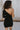 Close up back view of model wearing the Shelby Color Block Dress which features black and brown color blocked ribbed fabric, one long sleeve and one adjustable spaghetti strap.