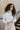 Front view of model wearing the Liana Mock Neck Top in Ivory, that features ivory ribbed fabric, high neckline, cropped waist and ribbed long sleeves.