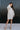 Full body front view of model wearing the Go Your Own Way Sweater Dress, that features beige knit fabric, a mock neckline, raglan balloon sleeves with ribbed cuffs, and a fitted ribbed hemline