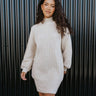 Front view of model wearing the Go Your Own Way Sweater Dress, that features beige knit fabric, a mock neckline, raglan balloon sleeves with ribbed cuffs, and a fitted ribbed hemline