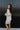 Side view of model wearing the Go Your Own Way Sweater Dress, that features beige knit fabric, a mock neckline, raglan balloon sleeves with ribbed cuffs, and a fitted ribbed hemline