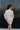 Back view of model wearing the Go Your Own Way Sweater Dress, that features beige knit fabric, a mock neckline, raglan balloon sleeves with ribbed cuffs, and a fitted ribbed hemline