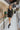 Full body front view of model wearing the Promise Me Dress, that has lined black fabric with a surplice neckline, a smocked waist, a tiered skirt, and semi-sheer long sleeves with a slight sheen and elastic wrists