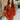 Front view of model wearing the Falling Fast Dress, that has rust-colored fabric, a v-neckline, ruffle details on the shoulders, long balloon sleeves with elastic wrists, and side pockets