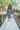 Full body front view of model wearing the Great Escape Denim Dress, that has washed black lightweight denim, a button-up front with silver buttons, a collared neckline, long sleeves with ruffled elastic wrists, and side pockets