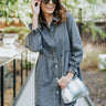 Front view of model wearing the Great Escape Denim Dress, that has washed black lightweight denim, a button-up front with silver buttons, a collared neckline, long sleeves with ruffled elastic wrists, and side pockets