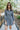 Front view of model wearing the Great Escape Denim Dress, that has washed black lightweight denim, a button-up front with silver buttons, a collared neckline, long sleeves with ruffled elastic wrists, and side pockets