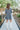 Full body back view of model wearing the Great Escape Denim Dress, that has washed black lightweight denim, a button-up front with silver buttons, a collared neckline, long sleeves with ruffled elastic wrists, and side pockets