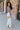 Full body side view of model wearing the So Over It Sweater, that has a beige, purple, blue, and olive digital striped pattern with orange lettuce trim, a cropped waist, long sleeves, and a round neckline.
