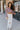 Full body front view of model wearing the So Over It Sweater, that has a beige, purple, blue, and olive digital striped pattern with orange lettuce trim, a cropped waist, long sleeves, and a round neckline.
