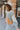 Side view of model wearing the Going West Sweater, that features ivory, peach, and light blue color blocking, a high round neckline, and long balloon sleeves with ribbed cuffs