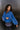 Frontal side view of model wearing the Long Live Sweatshirt, which features washed blue fabric, a 3/4 snap-up neckline with a small collar, raglan balloon sleeves with ribbed cuffs, and a ribbed hemline