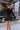 Front view of model wearing the What A Night Fringe Skirt, that features black satin fabric with silver beaded fringe, a wrap waist with a side tie, and a back zipper.