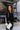 Front view of model wearing the Riley Waffle-Knit Top, which features black waffle knit fabric, raw hem details, scoop neckline, long sleeves with lettuce trim and drop shoulder.