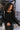 Front view of model wearing the Riley Waffle-Knit Top, which features black waffle knit fabric, raw hem details, scoop neckline, long sleeves with lettuce trim and drop shoulder.