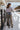 Full body back view of model wearing the All Or Nothing Cropped Blazer, that has brown and off white fabric with a plaid pattern, a cropped waist with a tortoise button closure, a collared neckline, and long sleeves.