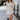 Full body front view of model wearing the Elodie Dress in Cream, which features cream ribbed fabric, a high neck with lettuce trim, long sleeves, and a flared skirt