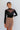 Front view of model wearing the See You There Tweed Skort, which features a multi-colored tweed fabric, a shorts back, and a front skirt overlay. Worn with black bodysuit