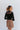 Back view of model wearing the See You There Tweed Skort, which features a multi-colored tweed fabric, a shorts back, and a front skirt overlay. Worn with black bodysuit