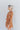 Side view of model wearing the Golden Hour Paisley Dress features camel-colored fabric with a paisley print, a surplice neckline, a tie belt and long sleeves with ruffled wrists