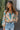 Front view of model wearing the First Love Floral Top, that has teal fabric with a metallic gold and ivory floral print, a surplice neckline, flowy balloon sleeves with smocked cuffs, and an elastic waist