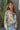 Front view of model wearing the First Love Floral Top, that has teal fabric with a metallic gold and ivory floral print, a surplice neckline, flowy balloon sleeves with smocked cuffs, and an elastic waist
