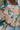 Close back view of model wearing the First Love Floral Top, that has teal fabric with a metallic gold and ivory floral print, a surplice neckline, flowy balloon sleeves with smocked cuffs, and an elastic waist