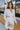 Front view of model wearing the My Type Blazer Dress, which features white fabric, a plunge neckline with a lapel &amp; a collar, long sleeves, a back zipper, and a front twist &amp; cutout detail