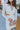 Close-up front view of model wearing the My Type Blazer Dress, which features white fabric, a plunge neckline with a lapel &amp; a collar, long sleeves, a back zipper, and a front twist &amp; cutout detail