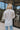 Back view of model wearing the For the Record Top, that features white fabric with a button-up front, a collared neckline, front chest pockets, and side slits.