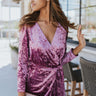 Front view of model wearing the Supernova Velvet Romper in Plum, which features light purple crushed velvet, a surplice neckline, a front skirt overlay with a side tie, and long fitted sleeves