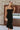 Front view of model wearing the Walk of Fame Midi Dress, which features patterned black velvet, black feathers across the neckline, adjustable thin straps, and a midi mermaid silhouette